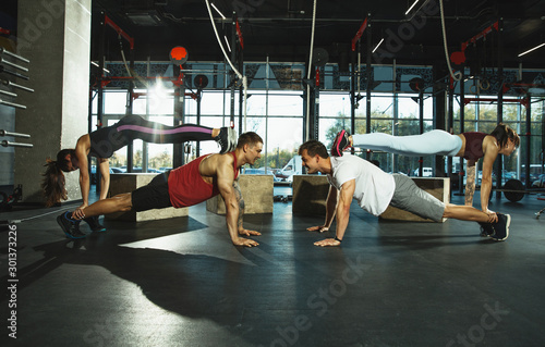 A group of muscular athletes doing workout at the gym. Gymnastics, training, fitness workout flexibility. Active and healthy lifestyle, youth, bodybuilding. Training upper and lower body. Support.