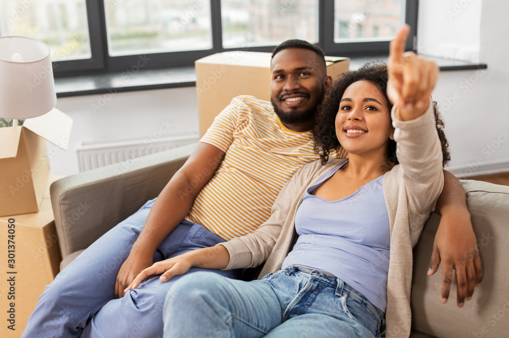 moving, people, repair and real estate concept - happy african american couple with cardboard boxes sitting on sofa at new home moving, people, repair and real estate concept - happy african american couple with cardboard boxes sitting on sofa at new home