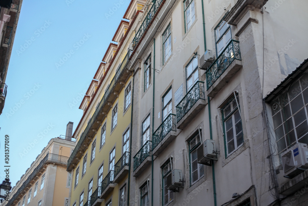 The traditional facade wall architectures of buildings with large glass doors and windows, balconies and iron lamps in the city of Rome in Italy