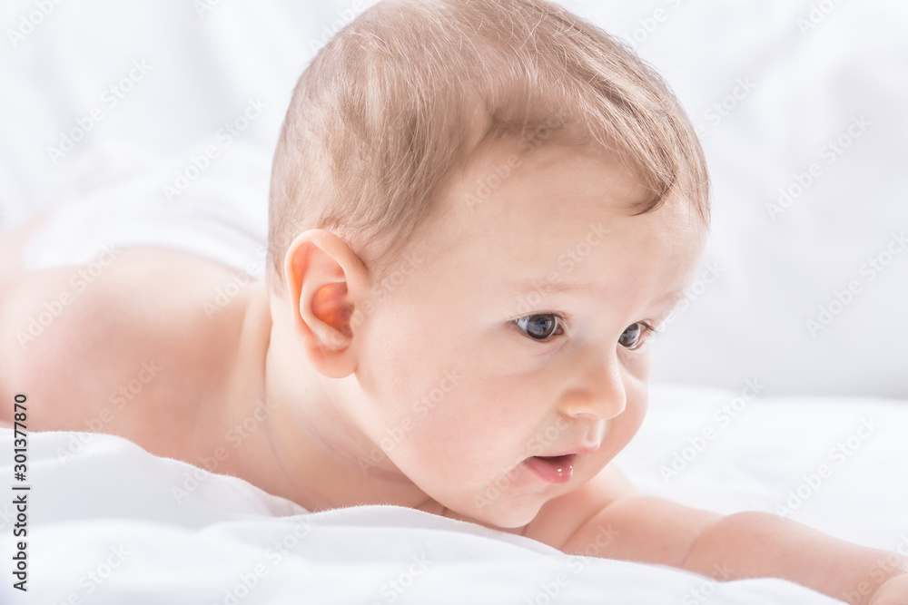 Portrait of cute toddler boy lying on bed. Newborn child in bedroom Portrait of cute toddler boy lying on bed. Newborn child in bedroom