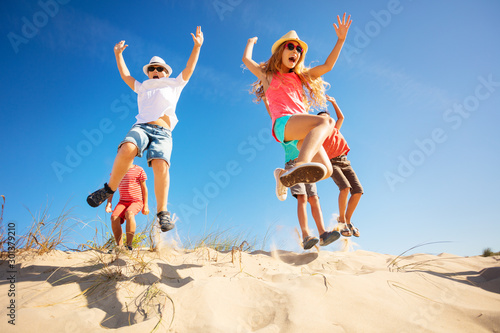 Sticker Group of children jump up from sand dune