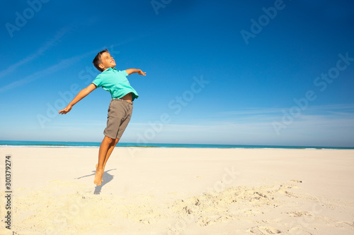 Relaxed and happy boy jump on the sand sea beach