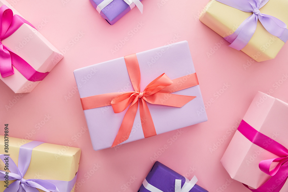 top view of colorful gift boxes with ribbons and bows on pink background top view of colorful gift boxes with ribbons and bows on pink background