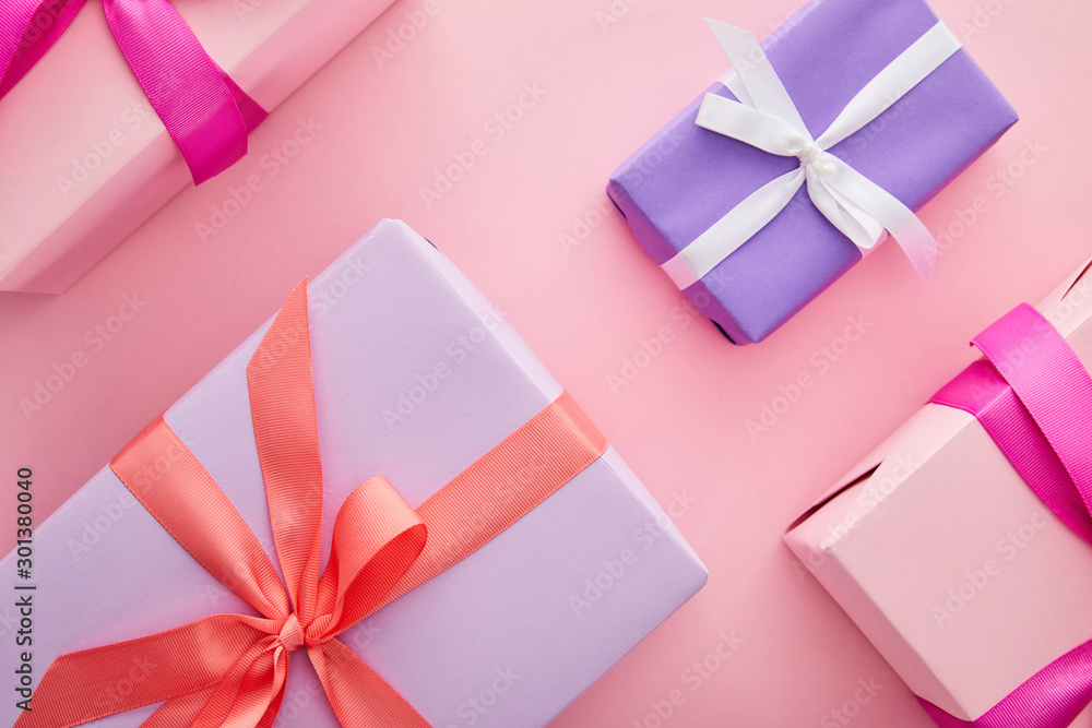flat lay with colorful gift boxes with ribbons and bows scattered on pink background flat lay with colorful gift boxes with ribbons and bows scattered on pink background