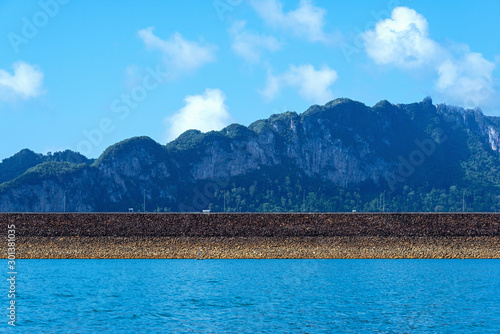 Rockfill dam with blue lake and limestone mountain range background photo