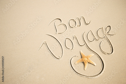 Canvas Print Bon Voyage message handwritten with a calligraphy script on a smooth sand beach