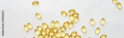 top view of golden fish oil capsules scattered on white background, panoramic shot photo