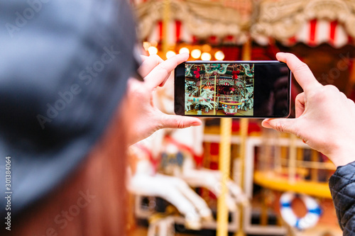 Girl takes pictures of carousel and horse figure