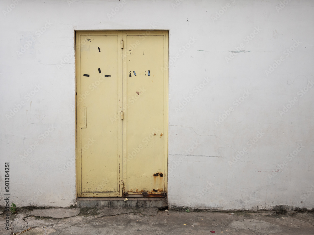 rusted yellow door in grungy concrete wall