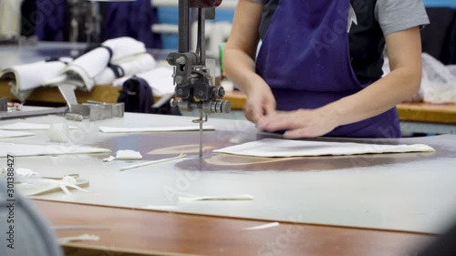 Close-up master at work on the machine for cutting fabric at the sewing factory. A sewing worker uses an electric cutting fabric machine. Industrial textile factory. 4k footage.