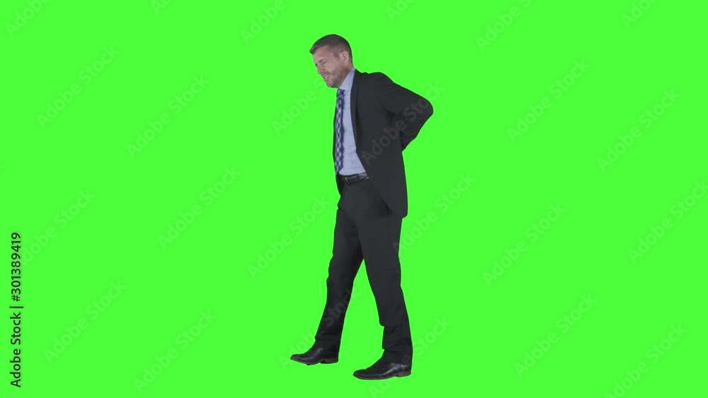 Caucasian businessman having back pain and walking back and forth in the studio. Sick worker concept. Shot in 4k resolution with green screen background Caucasian businessman having back pain and walking back and forth in the studio. Sick worker concept. Shot in 4k resolution with green screen background