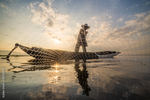 Picture of Asian fishermen on a wooden boat Thai fishermen catch fresh water fish in the natural river, traditional Thai fishermen at the morning sun on the lake of Thailand