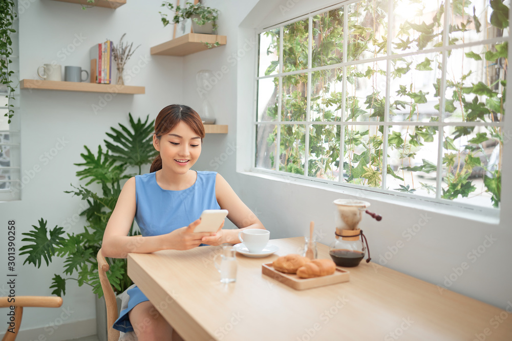 Asian woman using phone while having breakfast Asian woman using phone while having breakfast