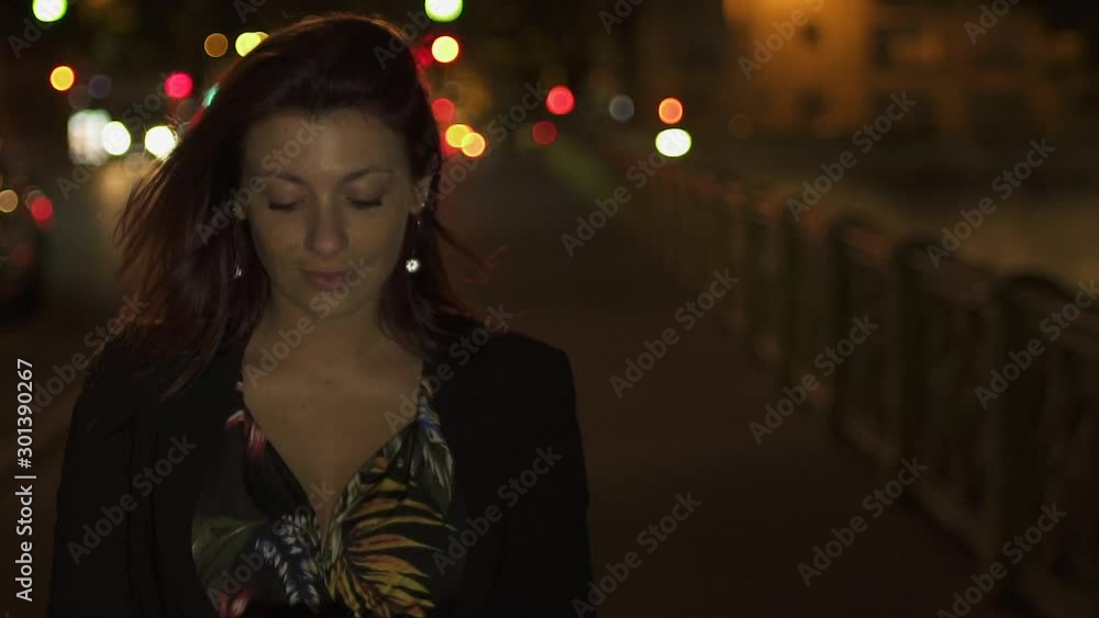 Cute Happy caucasian modern woman wearing flower dress, black jacket and red hair walking through the street and writing a text message on her smartphone by night. Paris 4K UHD. Slow Motion. Cute Happy caucasian modern woman wearing flower dress, black jacket and red hair walking through the street and writing a text message on her smartphone by night. Paris 4K UHD. Slow Motion.