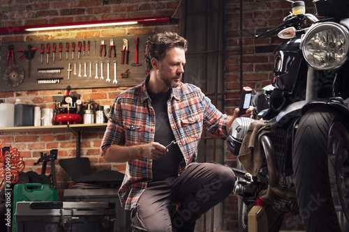 Attractive mechanic working on a vintage motorbike