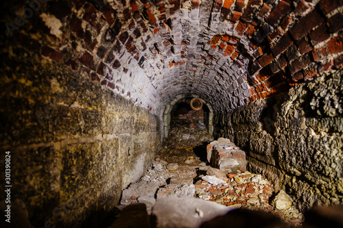 Old collapsed red brick underground vaulted historical sewer tunnel, selective focus © Mulderphoto
