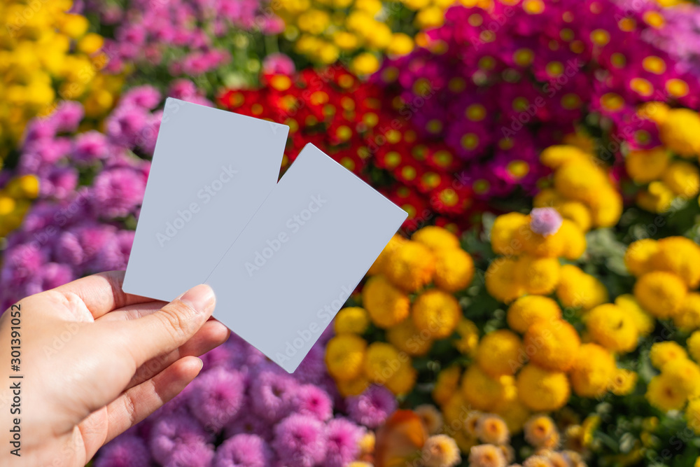 Hand holding two white polaroid paper photos with colorful flowers background Hand holding two white polaroid paper photos with colorful flowers background