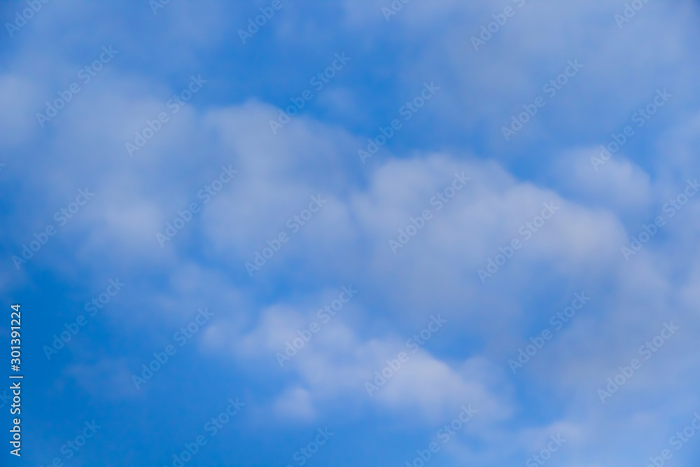 Beautiful white clouds on a background of blue sky. Defocused image for design.