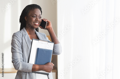 Black female job seeker talking on cellphone and holding CV photo