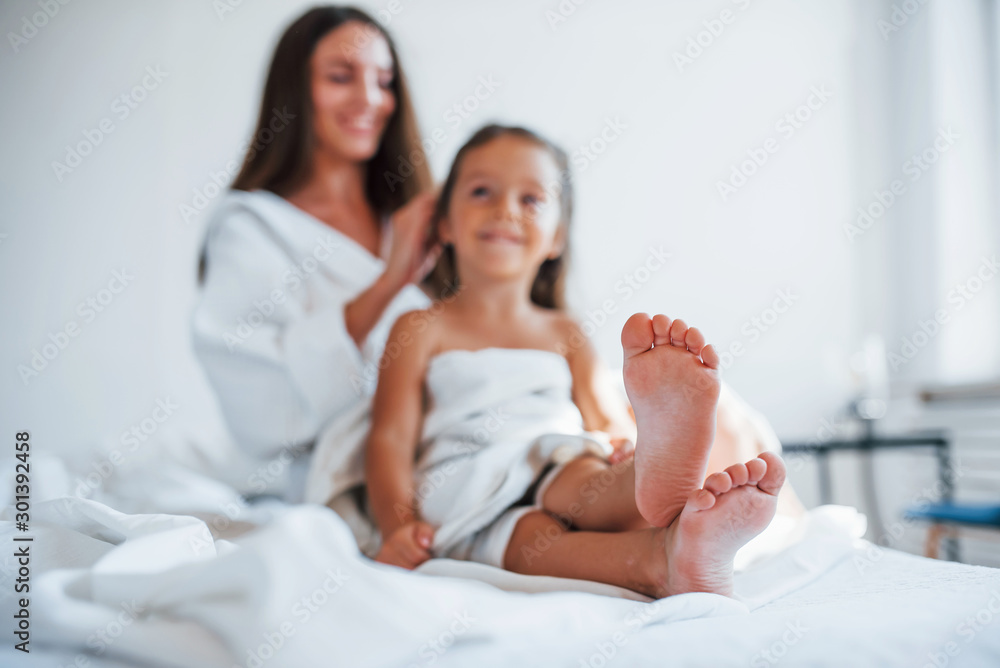 Focused photo. Young mother with her daugher have beauty day indoors in white room Focused photo. Young mother with her daugher have beauty day indoors in white room