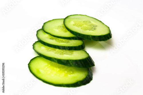 Ripe green cucumber on slices on a white background