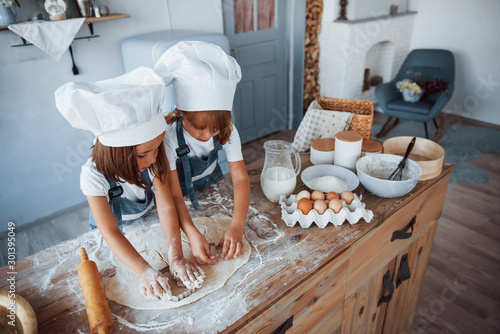 Family kids in white chef uniform preparing food on the kitchen