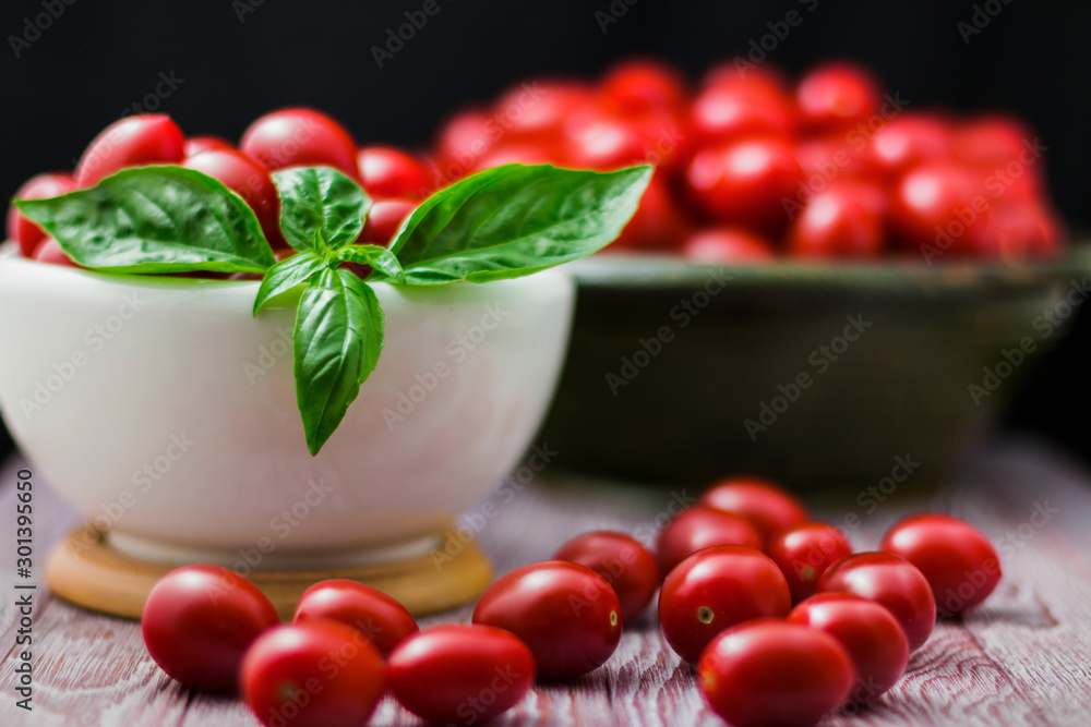 CHERY TOMATOES ON BLACK BACKGROUND WITH BASIL AND JUICE WITH SELECTIVE FOCUS CHERY TOMATOES ON BLACK BACKGROUND WITH BASIL AND JUICE WITH SELECTIVE FOCUS