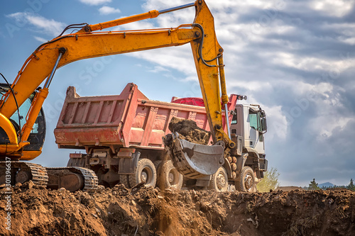 Fotografia Yellow excavator and empty dump truck working at the construction site