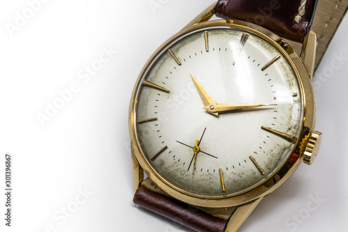 An old gold mechanical wristwatch with manual winding. Antique watch ruined by time, with scratches and mildew stains, rust, oxidation. Leather strap (band). Vintage clock. Spend time.