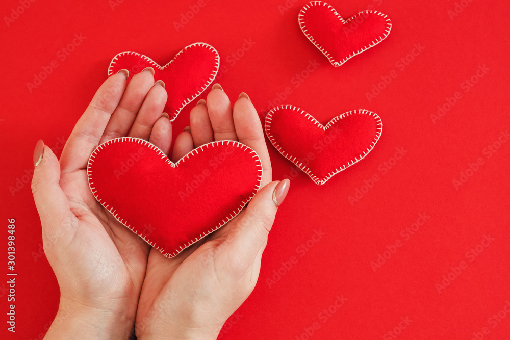 Romantic greeting card. Top view of handmade felt heart in woman hands over red background. Copy space. Romantic greeting card. Top view of handmade felt heart in woman hands over red background. Copy space.