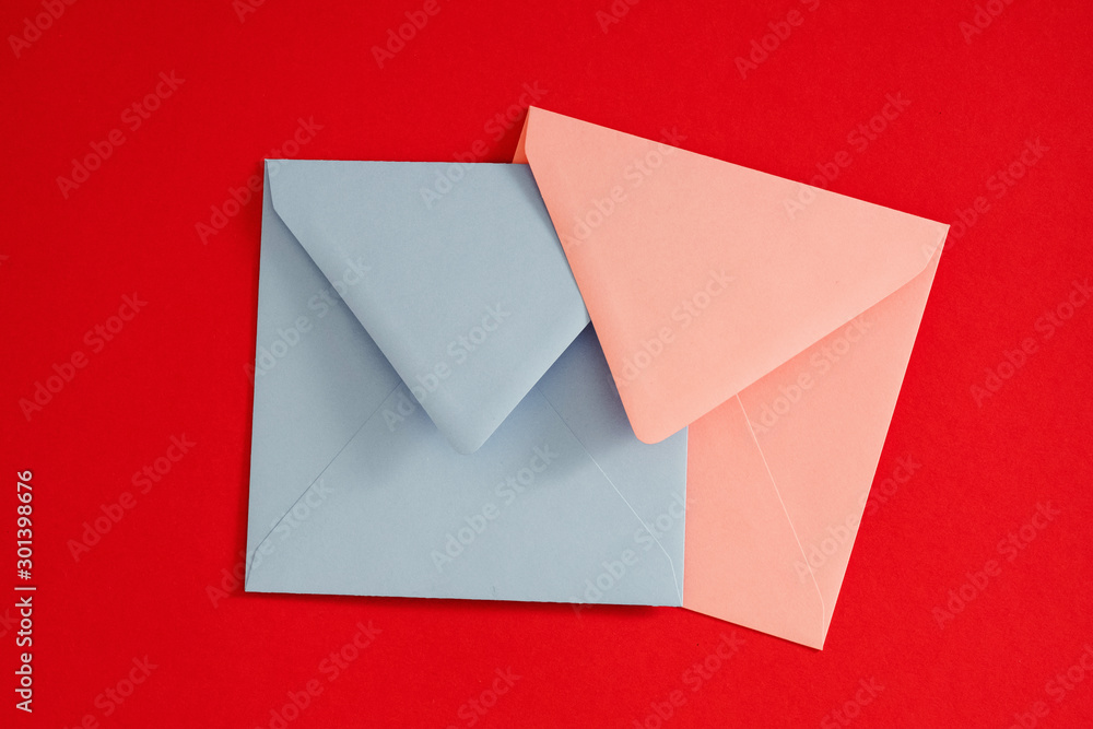 Romantic mail. Flat lay of pale blue and pink blank envelopes on red background. Copy space. Romantic mail. Flat lay of pale blue and pink blank envelopes on red background. Copy space.