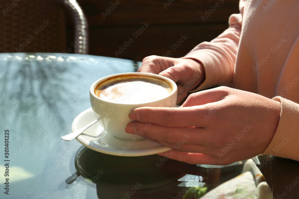 Woman with cup of fresh aromatic coffee at table in cafe
