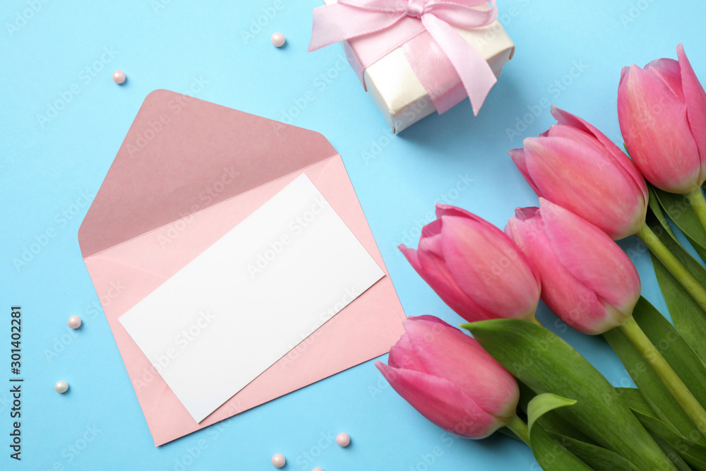Flat lay composition with tulips and card on light blue background, space for text. Happy Mother's day