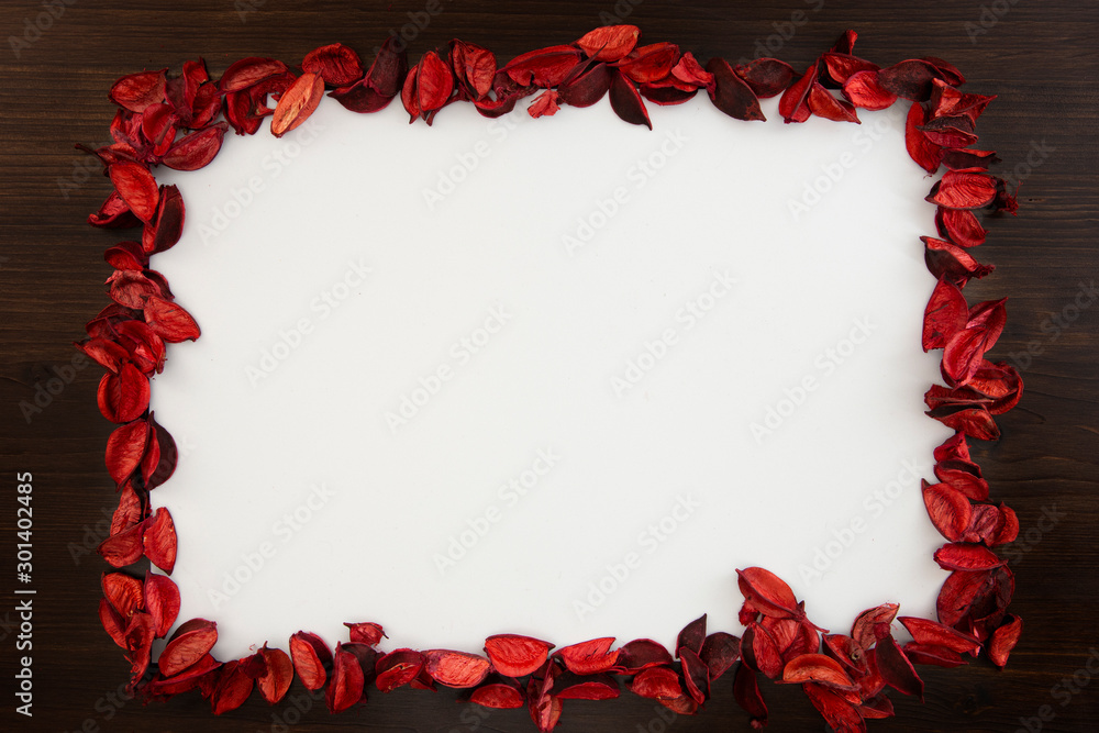 Flat lay Christmas copy space space with red petals bordering a white background and dark wood all around Flat lay Christmas copy space space with red petals bordering a white background and dark wood all around