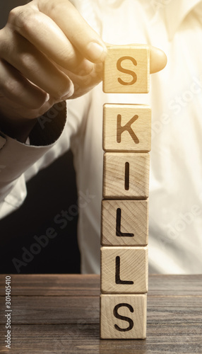 A man puts wooden blocks with the word Skills. Knowledge and skill. Self improvement. Education concept. Training. Leadership skills. Human abilities photo