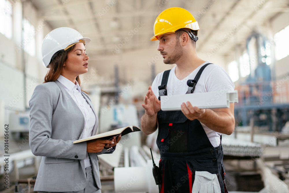 Architect and worker working on project. Colleagues discussing work in factory. Architect and worker working on project. Colleagues discussing work in factory.