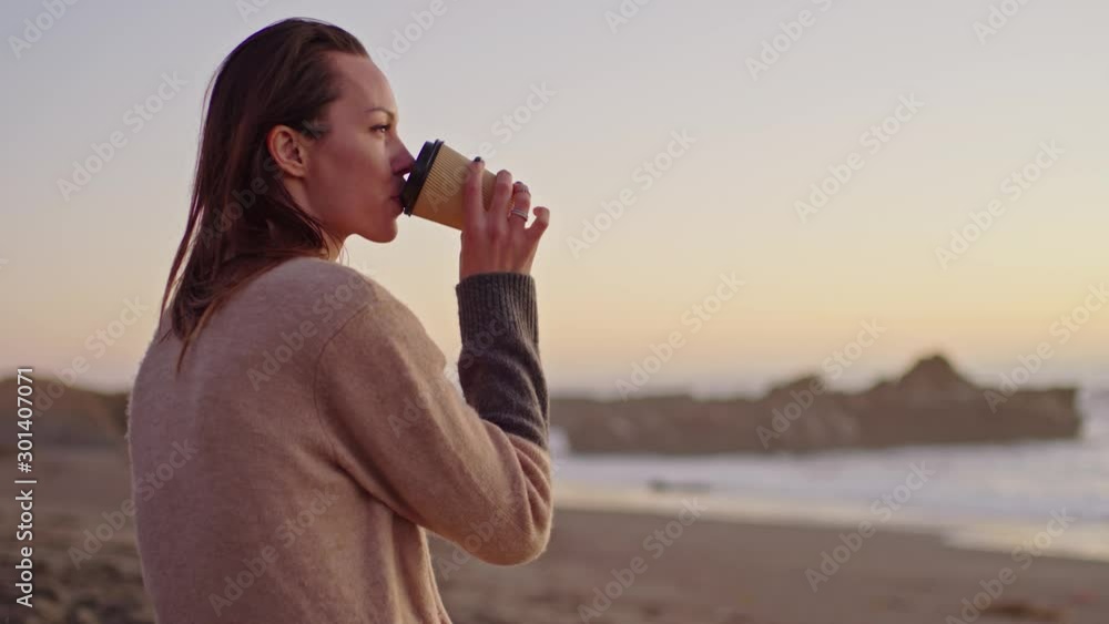 Woman enjoying hot drink on a sunset near ocean Woman enjoying hot drink on a sunset near ocean