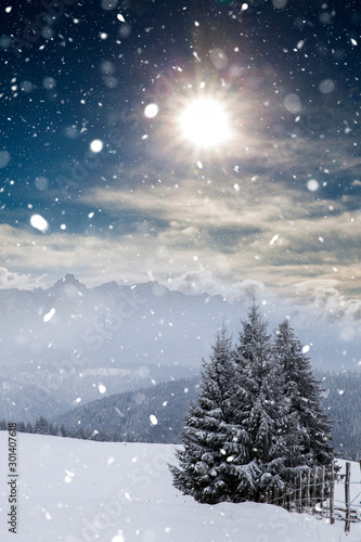 Christmas background with snowy fir trees and mountains in heavy blizzard.