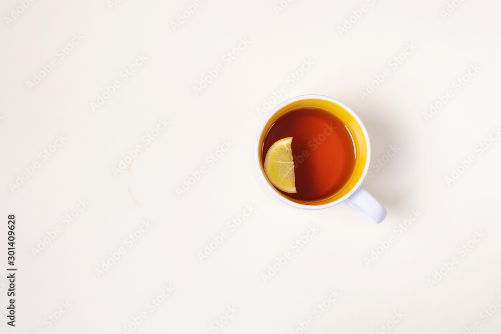 Cup with tea with lemon on a beige background. The concept of hot winter drinks. Top view, minimalism, flat lay. Place for text.