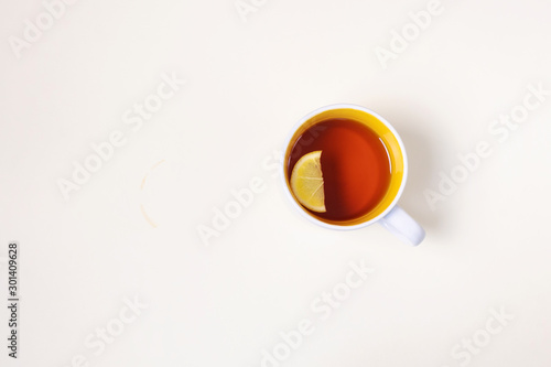 Cup with tea with lemon on a beige background. The concept of hot winter drinks. Top view, minimalism, flat lay. Place for text.