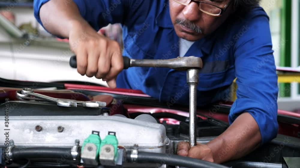 Auto mechanic tighten bolt of engine car with torque wrench in automobile garage.maintenance and adjustment Auto mechanic tighten bolt of engine car with torque wrench in automobile garage.maintenance and adjustment
