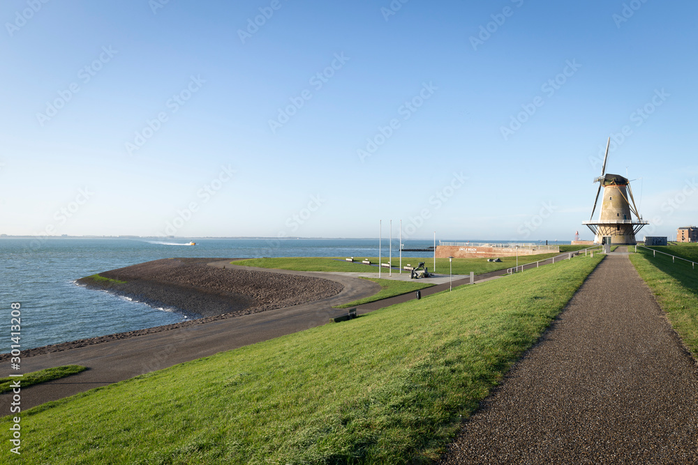 Dutch landscape in Vlissingen with sea, dyke and windmill Dutch landscape in Vlissingen with sea, dyke and windmill