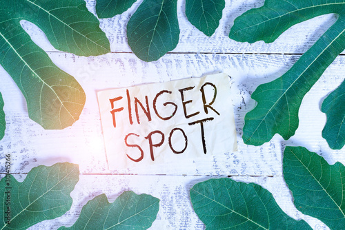 Conceptual hand writing showing Finger Spot. Concept meaning Small fluidfilled blisters called vesicles appear on the finger Leaves surrounding notepaper above a classic wooden table photo