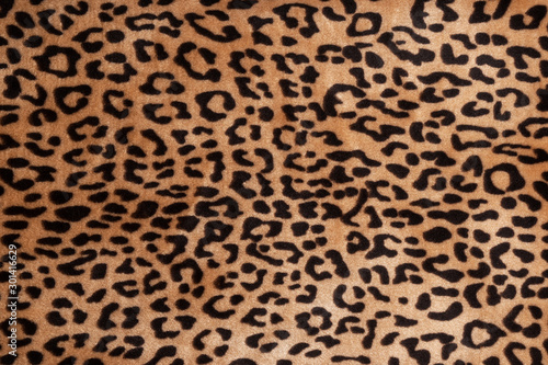 Faux fur leopard texture background. Fashionable modern ecological material. Plaid or carpet.