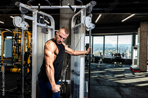 Fotografie Young muscular sweaty fit man doing triceps workout training in the gym for big