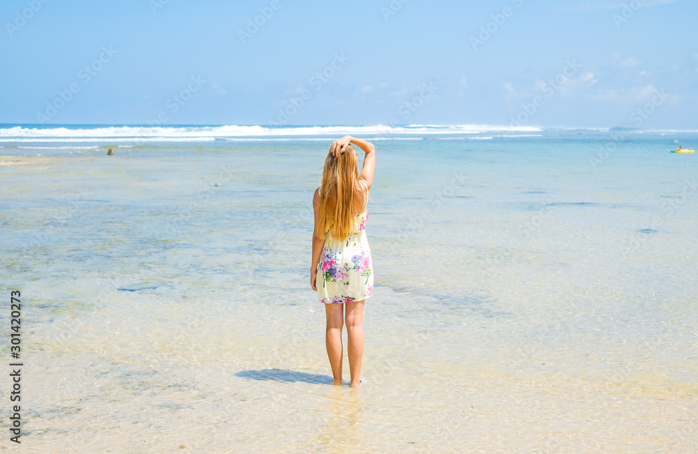 A girl in a dress stands in the summer on the ocean. A girl in a dress stands in the summer on the ocean.