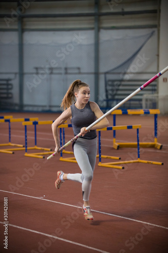 Pole vaulting indoors - young woman running with a pole in the hands © KONSTANTIN SHISHKIN
