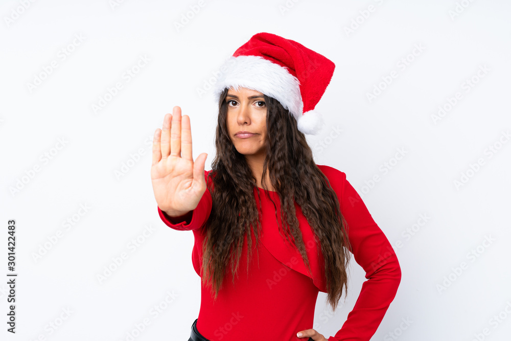 Girl with christmas hat over isolated white background making stop gesture with her hand
