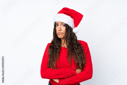 Girl with christmas hat over isolated white background having doubts and with confuse face expression