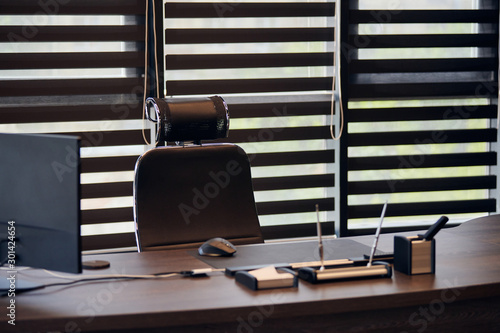 Business office workplace. Work place for chief, boss or other employees. Table and comfortable chair. Light through the half open blinds